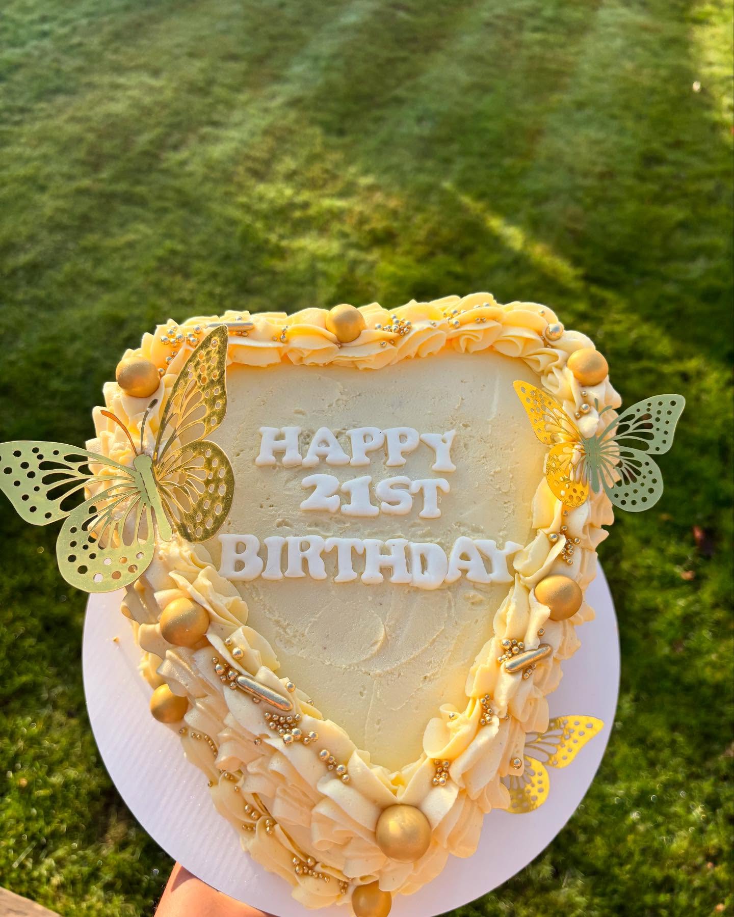 A cream heart-shaped 21st birthday cake with gold butterflies